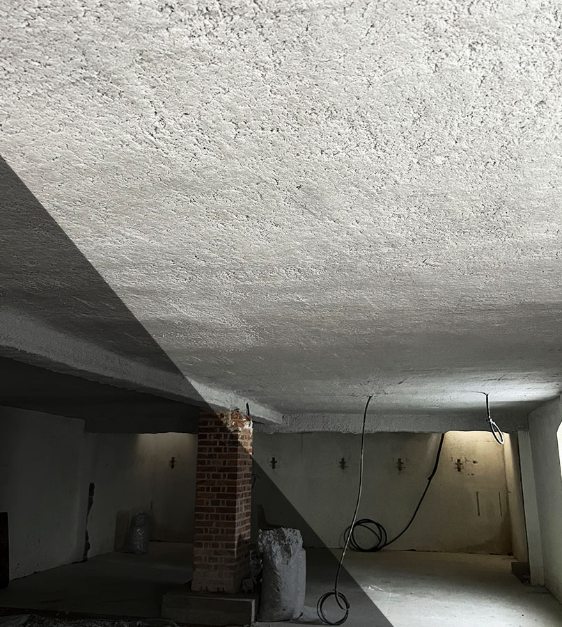 isolation-thermique-chantier Isolation thermique d’un plafond de sous-sol par projection de laine minérale, dans le cadre d’un chantier de rénovation énergétique de bâtiment professionnel.