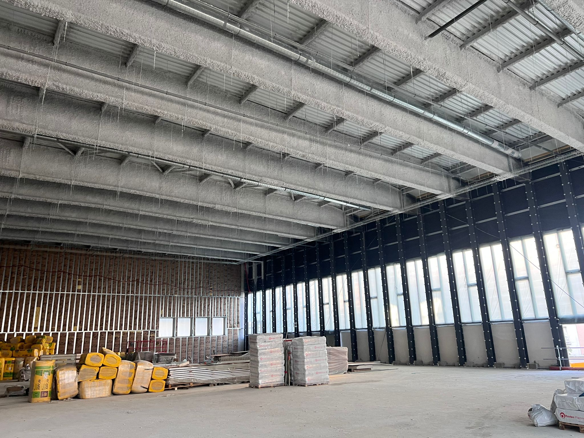 Intérieur de chantier : plafond ignifugé avec glaçons. Ossature métallique, fenêtres provisoires et matériaux IS A KNAUF / Protec Fiamm.